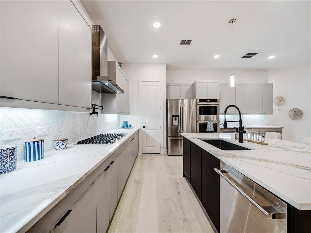 2313 Peters Colony Drive, Little Elm, TX 75036 Kitchen with modern cabinets, appliances with stainless steel finishes, light stone countertops, hanging light fixtures, and recessed lighting