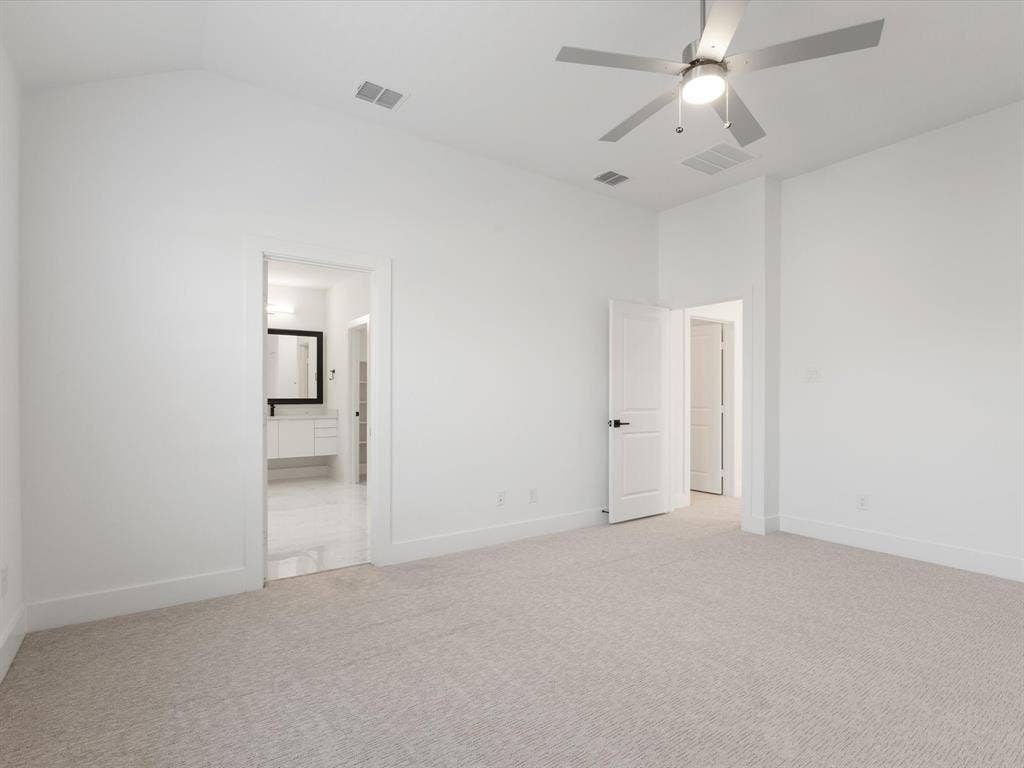 Primary bedroom with carpet, a ceiling fan, ensuite bath, and vaulted ceiling