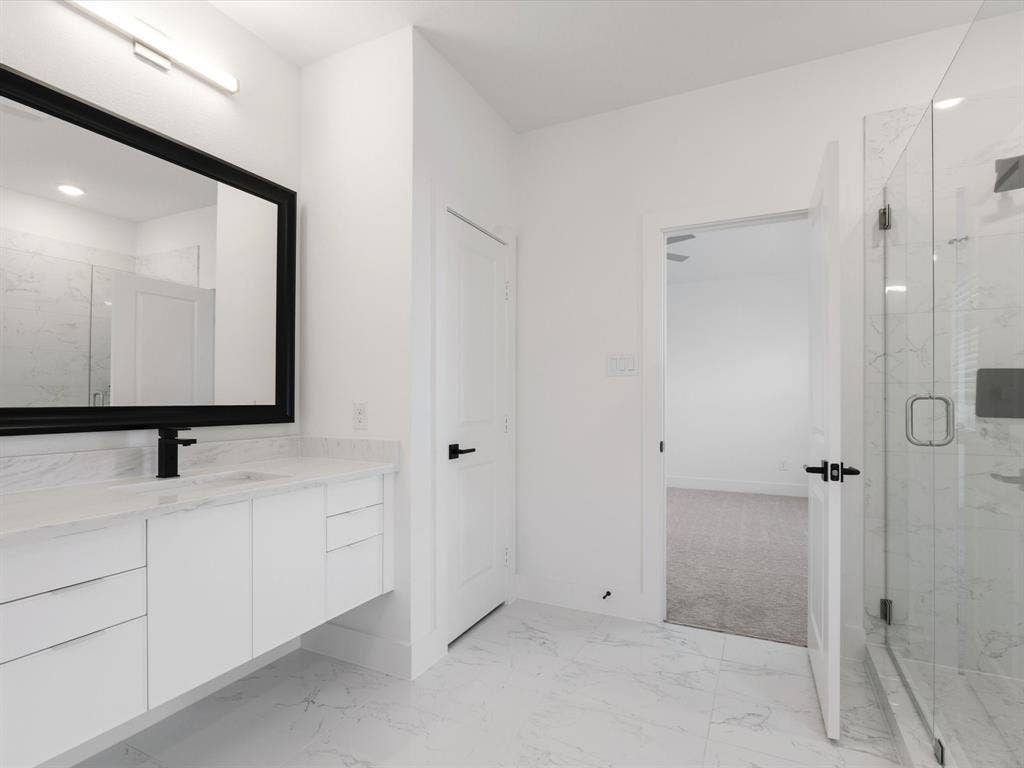 Primary Bathroom featuring vanity, a marble finish shower, and light marble finish floors