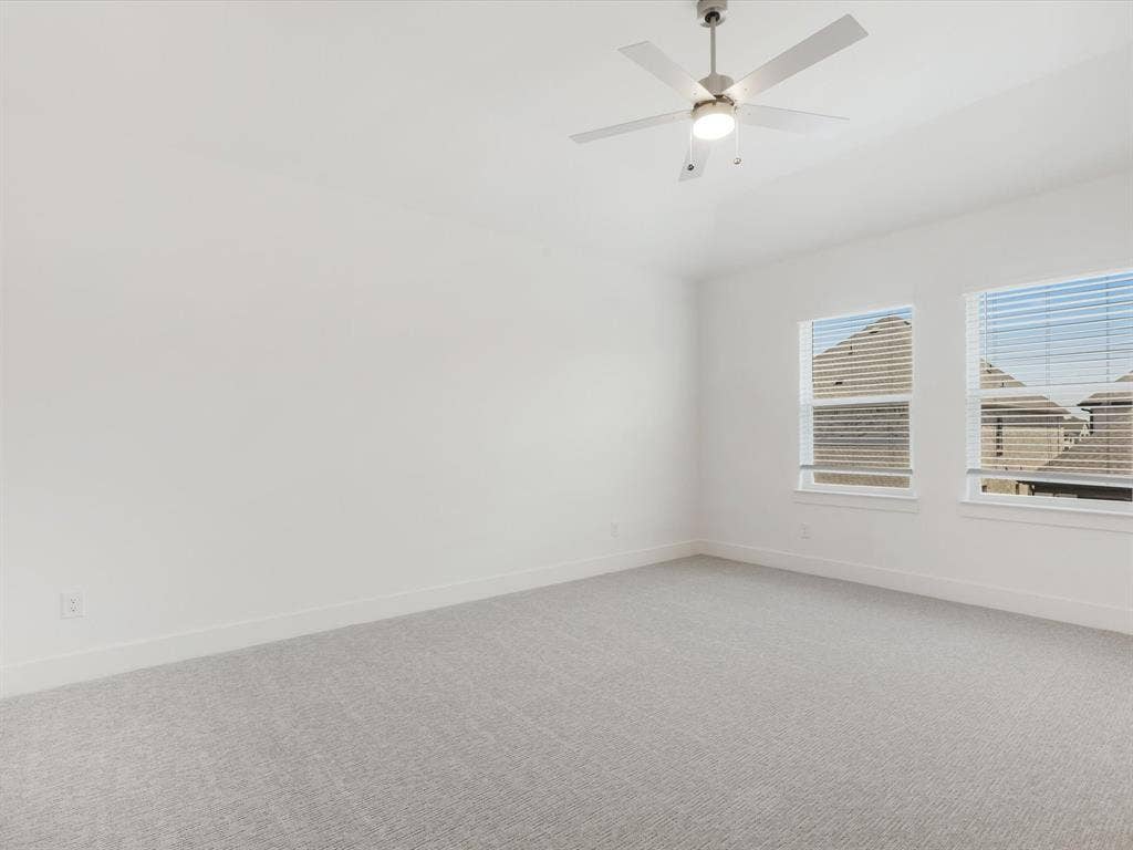 Primary bedroom with light colored carpet and ceiling fan