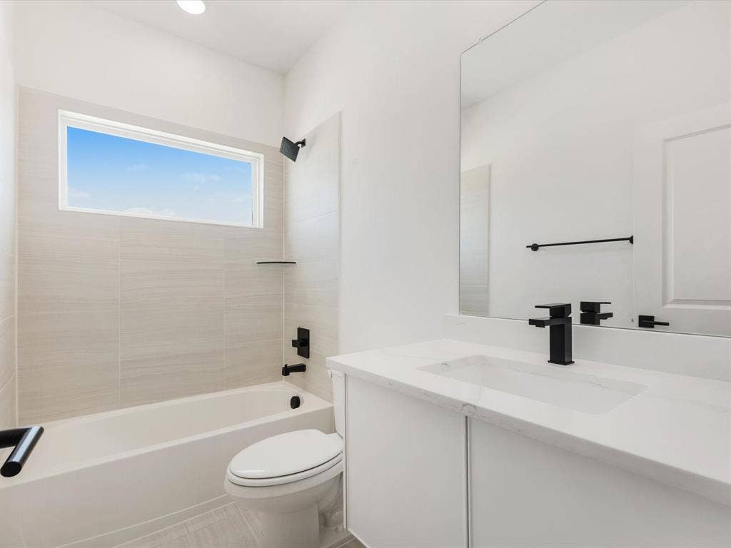 Ensuite bath featuring bathing tub / shower combination, vanity, and light tile patterned flooring