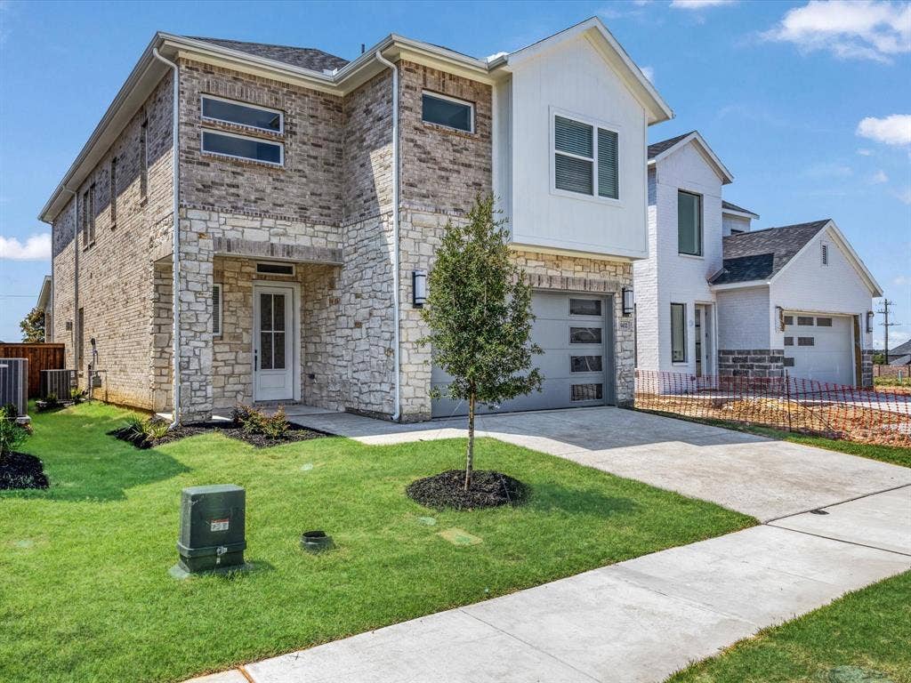 View of front facade featuring stone siding, driveway, an attached garage, and brick siding
