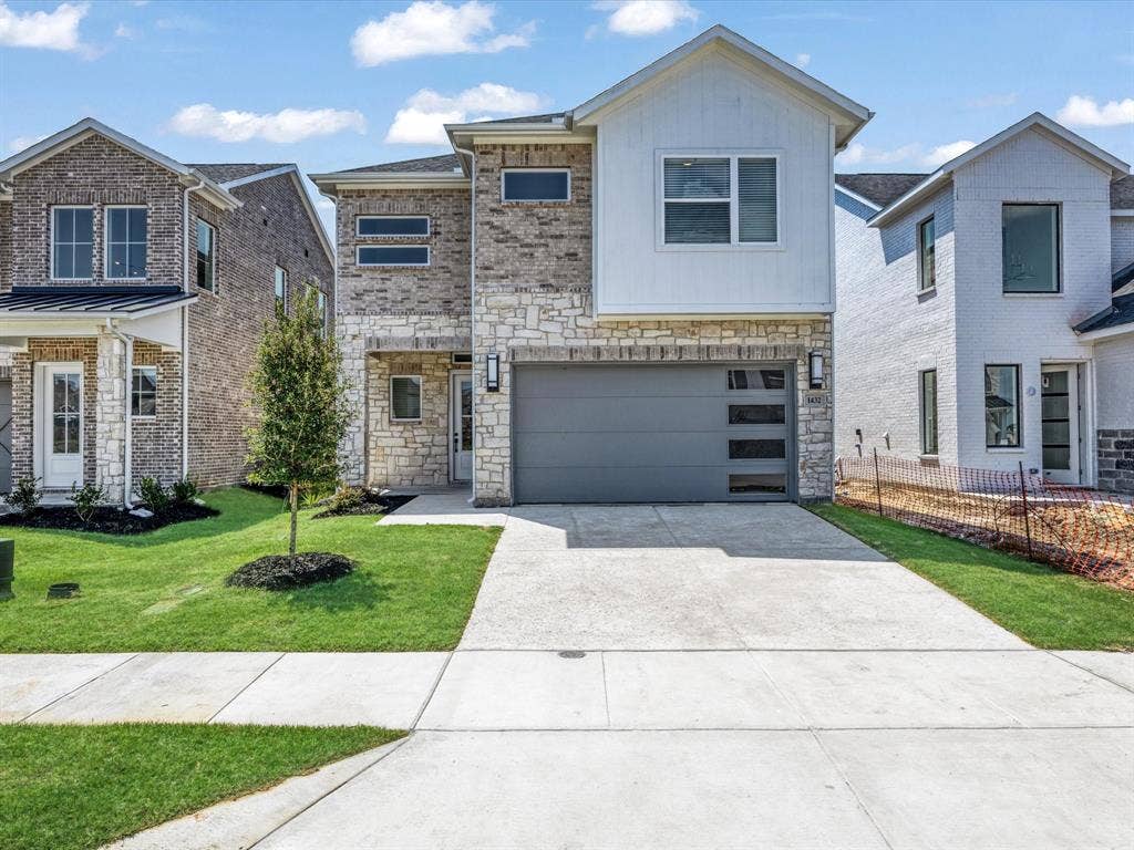 View of front of property featuring concrete driveway, stone siding, a garage, and a front yard
