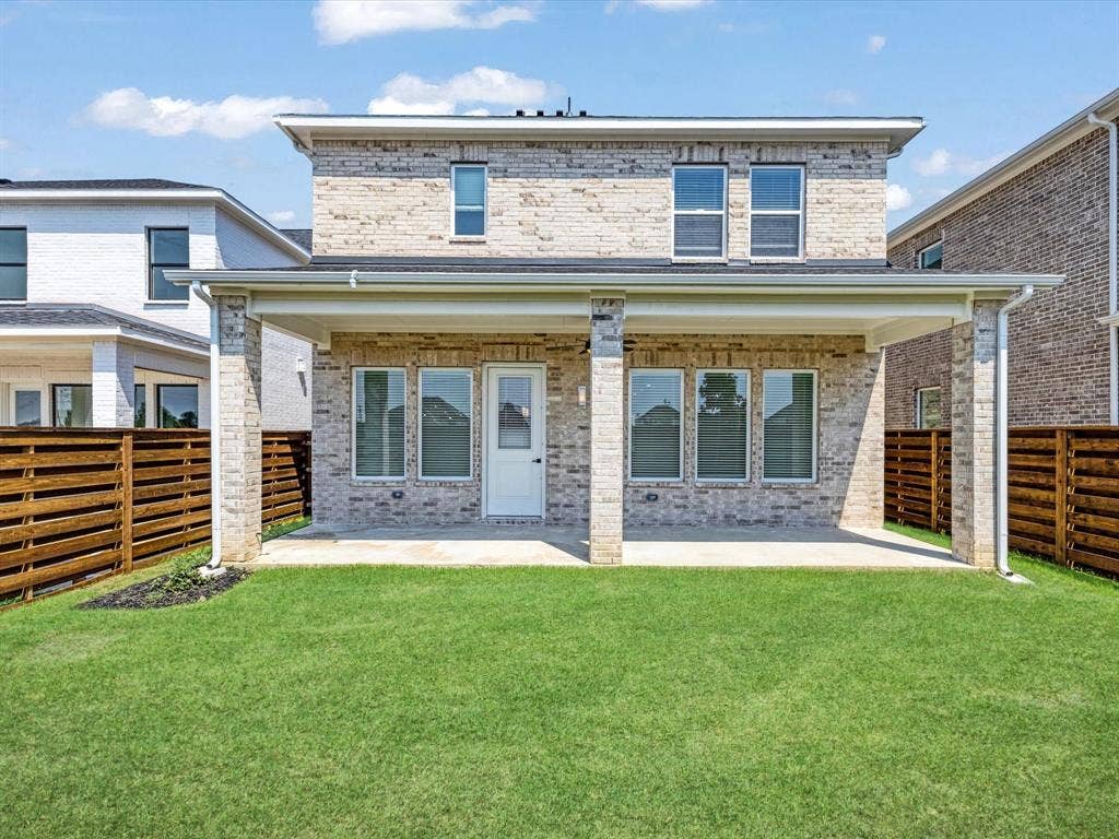 Back of property featuring brick siding, a fenced backyard, and a patio area