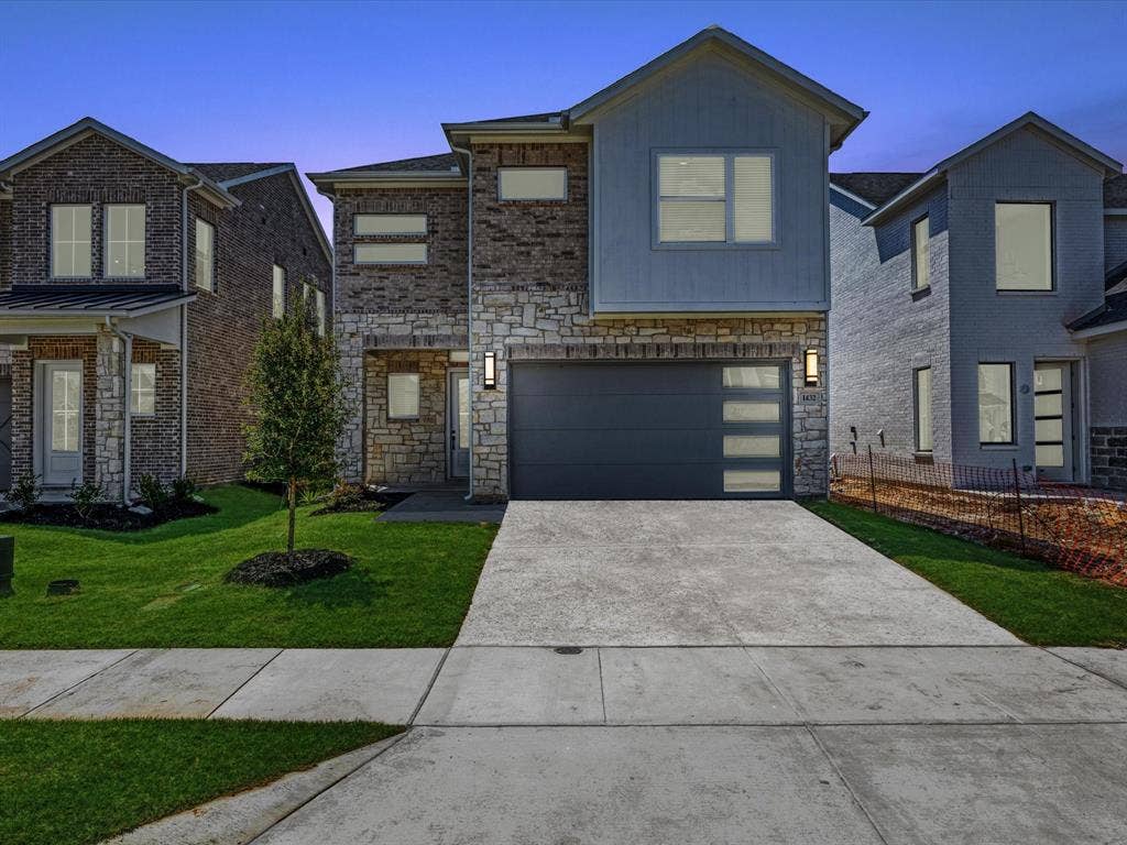 View of front of home with concrete driveway, stone siding, an attached garage, and a front lawn