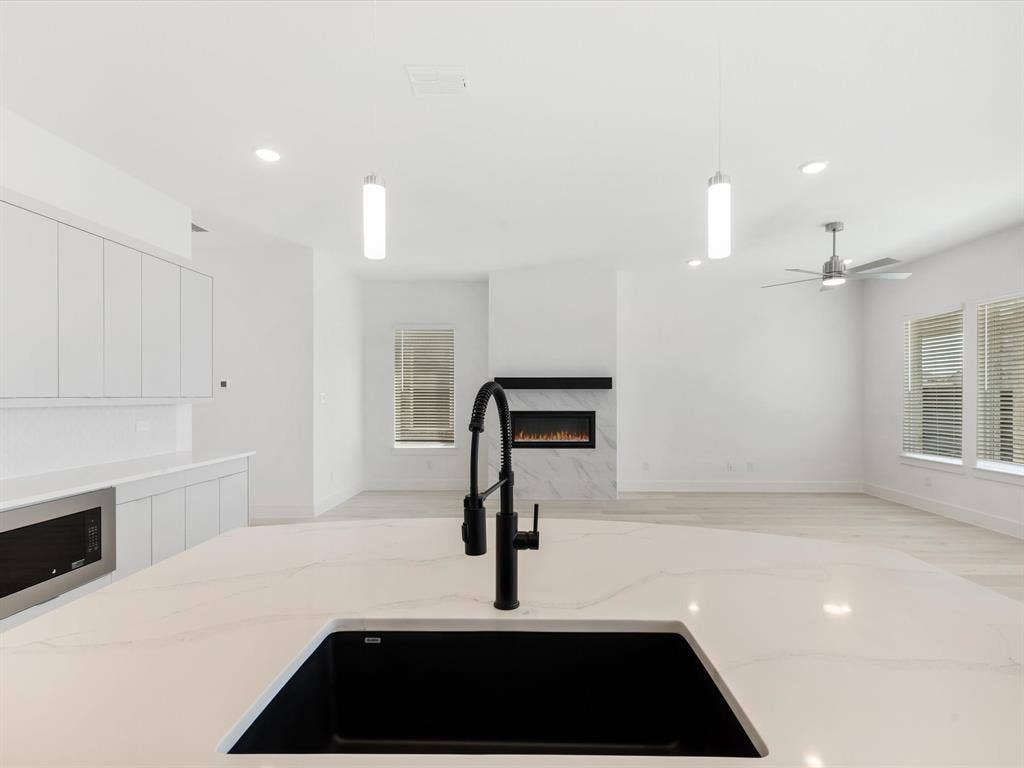Kitchen featuring decorative light fixtures, recessed lighting, white cabinetry, and a premium fireplace