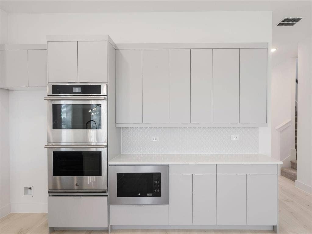 Kitchen with appliances with stainless steel finishes, modern cabinets, light wood-style floors, white cabinetry, and recessed lighting