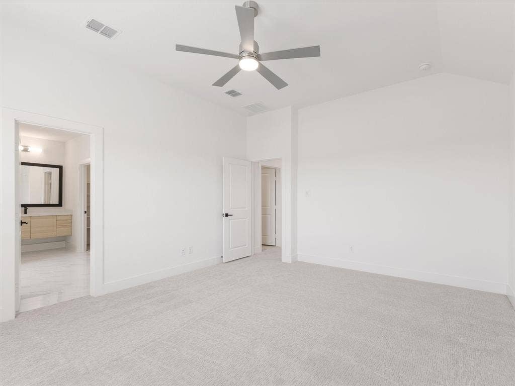 Primary bedroom with carpet flooring, ceiling fan, connected bathroom, and vaulted ceiling