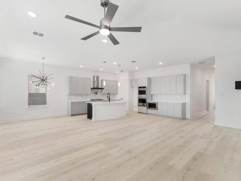 Spacious Living room featuring light wood-style floors, a chandelier, recessed lighting, and a ceiling fan