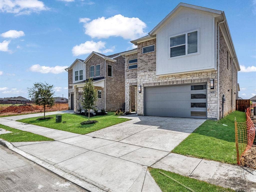 View of front of house with a front lawn, stone siding, concrete driveway, and an attached garage