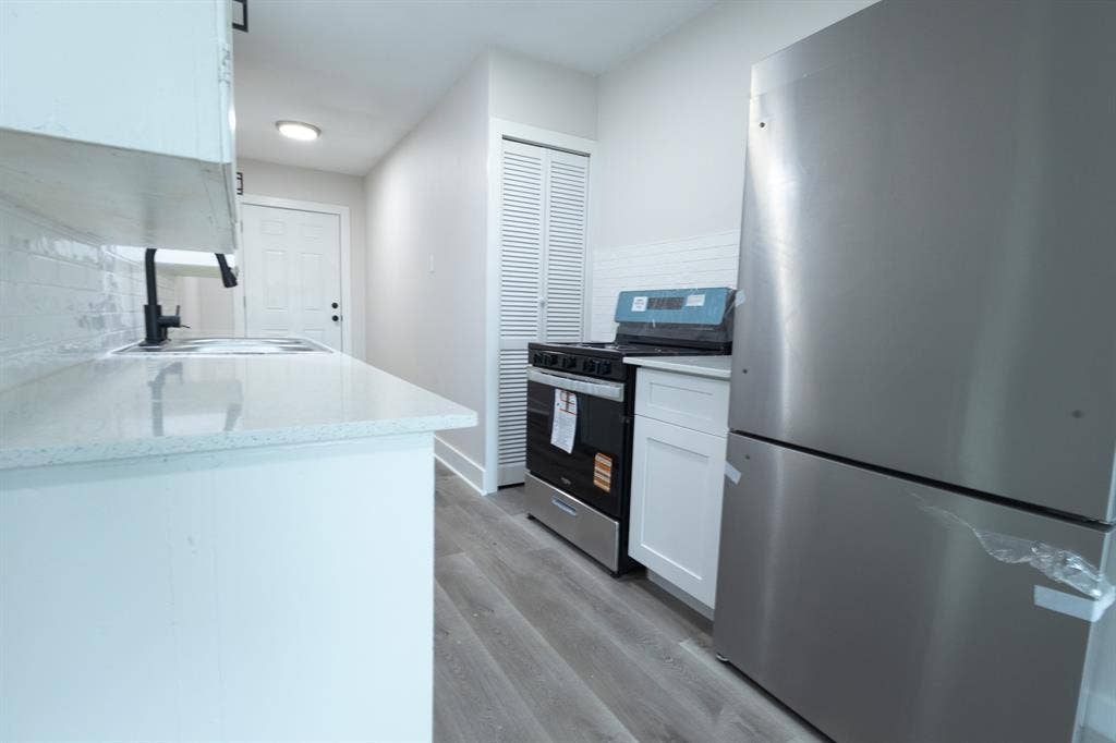 1716 Ethel Avenue, #1714, 1718, 1720, Waco, TX 76707 Kitchen featuring quartz countertops, white cabinetry, wood-finish flooring, a stainless steel refrigerator, and a black range