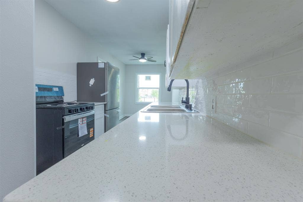 1716 Ethel Avenue, #1714, 1718, 1720, Waco, TX 76707 White solid surface countertops, subway tile backsplash, stainless steel refrigerator, black range, and dual basin sink with black hardware
