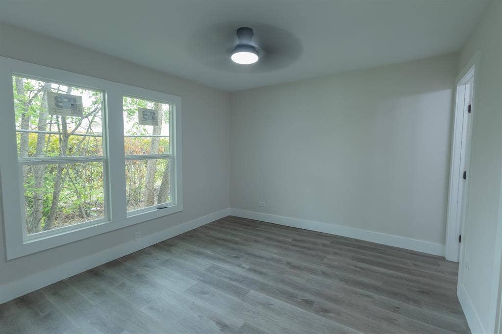 1716 Ethel Avenue, #1714, 1718, 1720, Waco, TX 76707 Neutral wall paint, wood-finish flooring, two large windows, white door frame, and a flush-mount ceiling light fixture