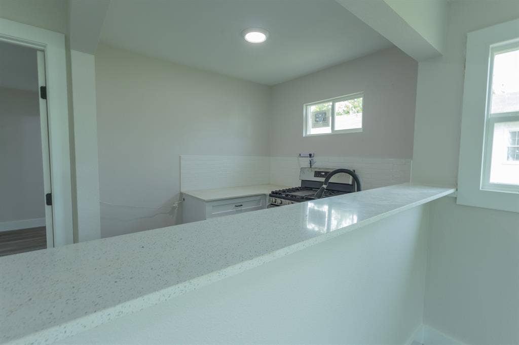 1716 Ethel Avenue, #1714, 1718, 1720, Waco, TX 76707 Kitchen featuring a gas range, subway tile backsplash, white cabinetry, and light-toned countertops