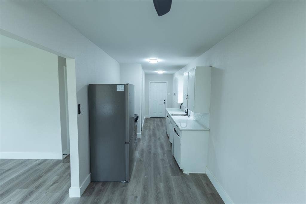 1716 Ethel Avenue, #1714, 1718, 1720, Waco, TX 76707 Galley kitchen featuring white cabinetry, light countertops, integrated sink, and stainless steel refrigerator
