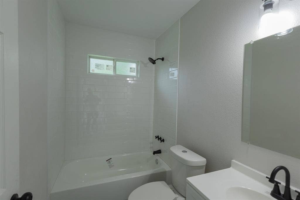 1716 Ethel Avenue, #1714, 1718, 1720, Waco, TX 76707 White subway tile shower surround with a built-in tub, black shower fixtures, vanity with integrated sink, and wall-mounted mirror