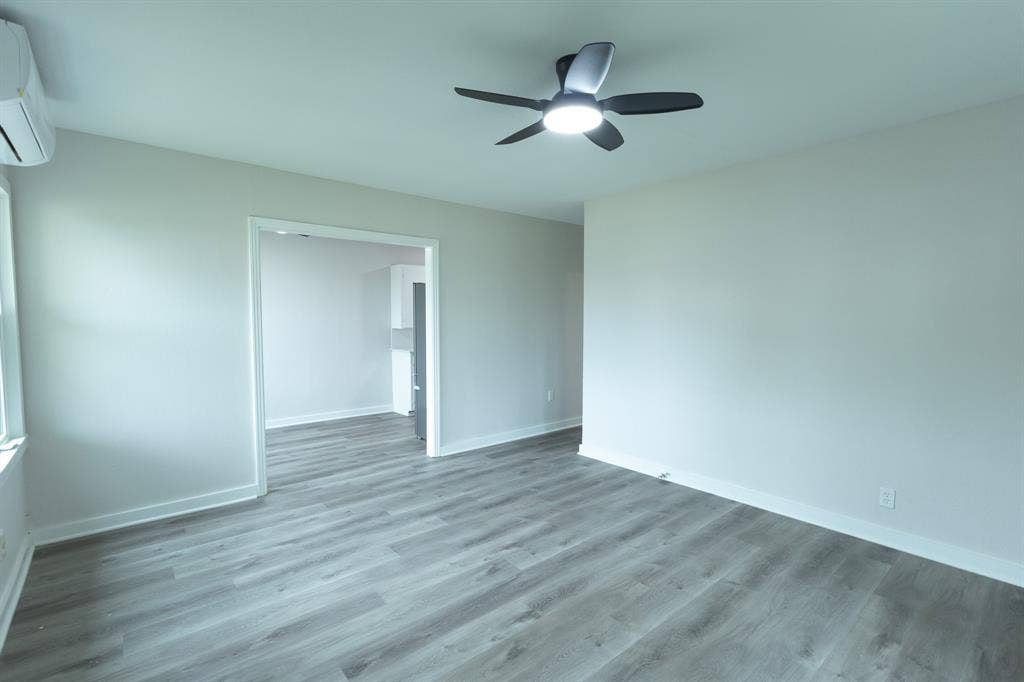 1716 Ethel Avenue, #1714, 1718, 1720, Waco, TX 76707 Wood-finish flooring, ceiling fan with integrated lighting, white trim, and a wall-mounted climate control unit