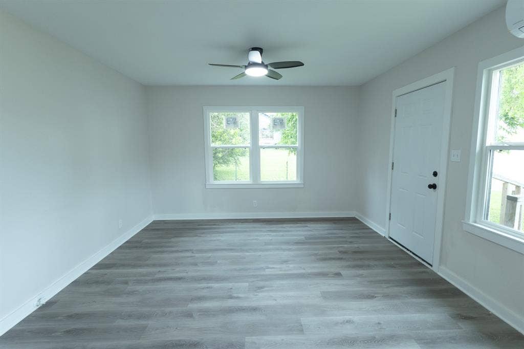 1716 Ethel Avenue, #1714, 1718, 1720, Waco, TX 76707 Bright, light-filled bedroom showcasing wood-finish flooring, ceiling fan with integrated lighting, and multiple windows providing natural illumination