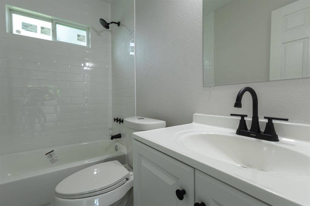1716 Ethel Avenue, #1714, 1718, 1720, Waco, TX 76707 White subway tile shower surround, matte black fixtures, white vanity with integrated sink, and a rectangular wall mirror