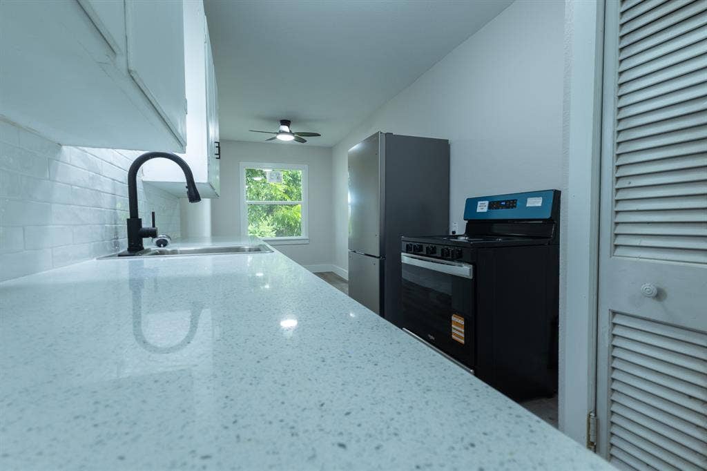 1716 Ethel Avenue, #1714, 1718, 1720, Waco, TX 76707 Kitchen featuring a stainless steel sink, matte black faucet, subway tile backsplash, white cabinetry, and light-toned countertops