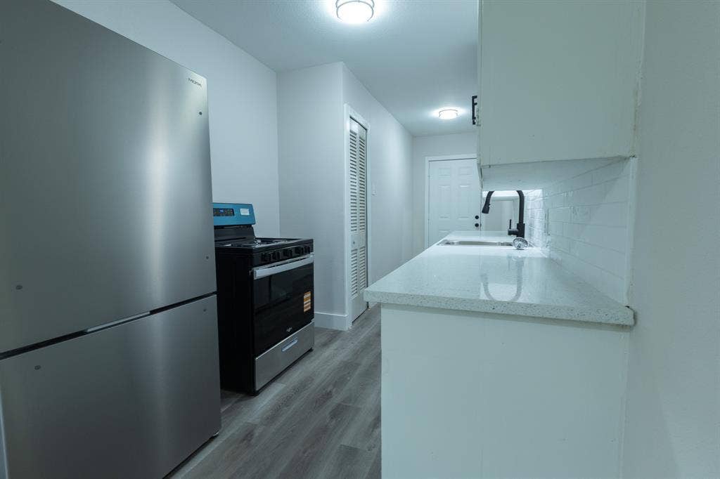 1716 Ethel Avenue, #1714, 1718, 1720, Waco, TX 76707 Stainless steel refrigerator and range, white shaker-style cabinetry, solid surface countertops, white subway tile backsplash, and wood-finish flooring