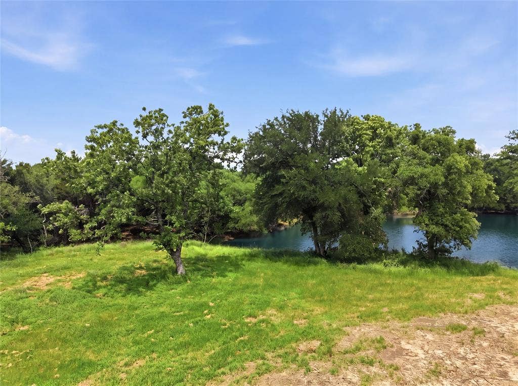 TBD Manley Road, Weatherford, TX 76088 Expansive grassy area featuring mature trees and a tranquil body of water