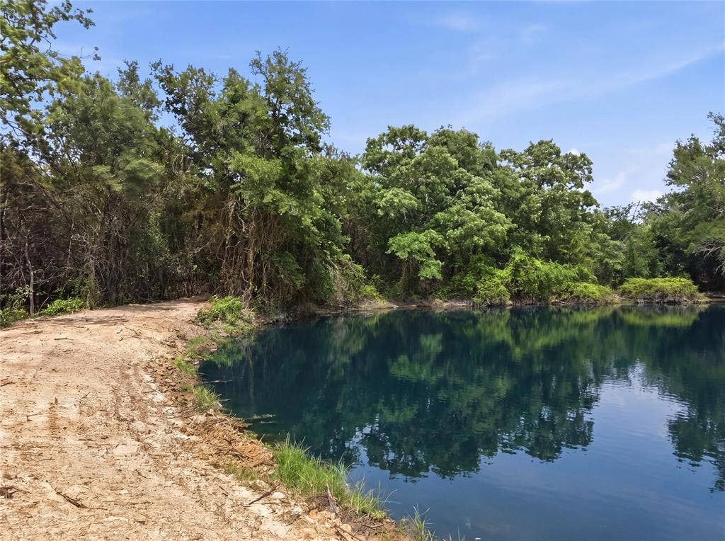 TBD Manley Road, Weatherford, TX 76088 Natural pond with clear water reflecting surrounding foliage, framed by established trees and a partially cleared bank