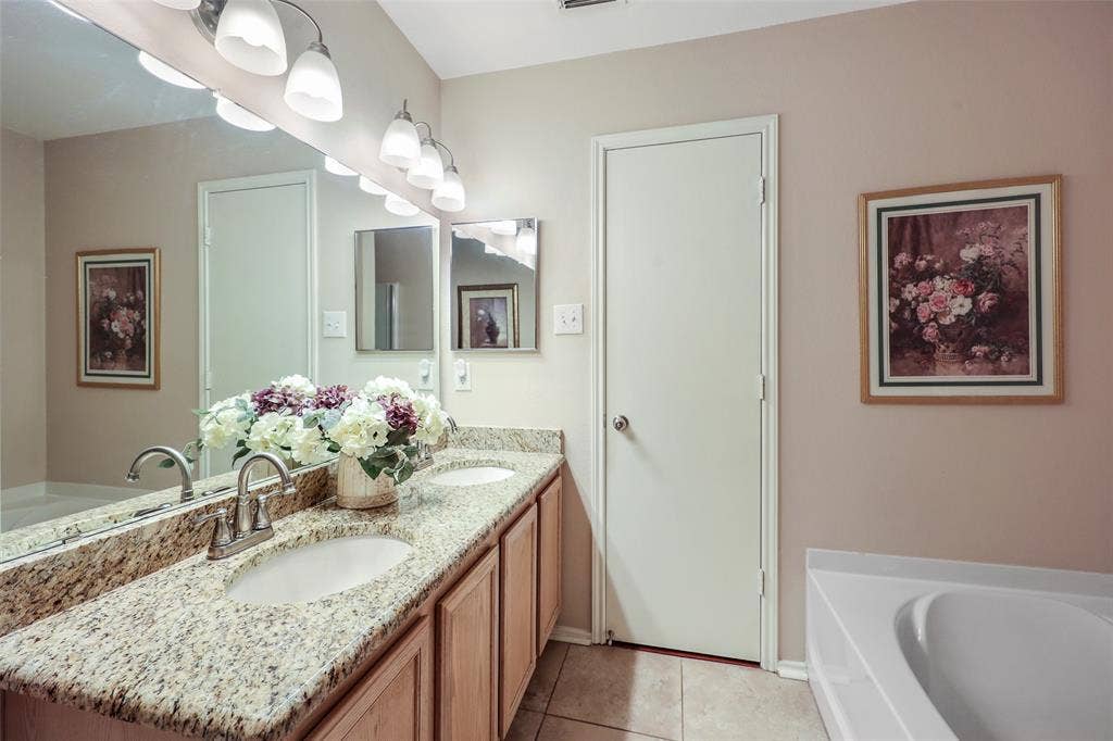 5409 Running Brook Lane, McKinney, TX 75071 Spa-inspired primary bathroom featuring dual vanity with granite countertop, polished nickel fixtures, and ample storage
