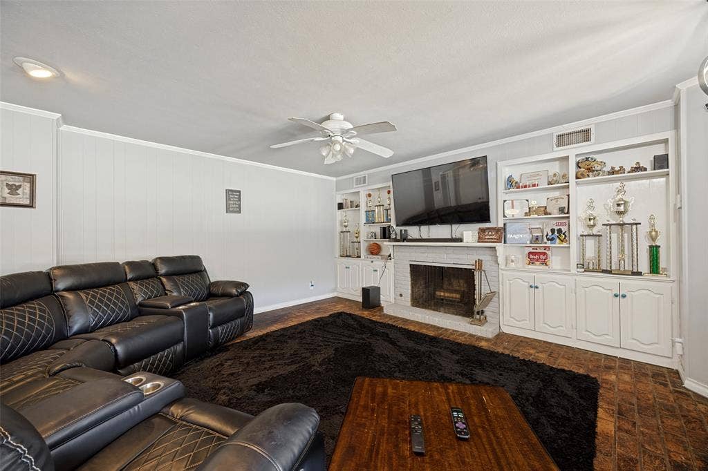 6401 Stonewall Street, Greenville, TX 75402 Living room featuring a white brick fireplace, built-in shelving, wood-finish flooring, a ceiling fan, and recessed lighting