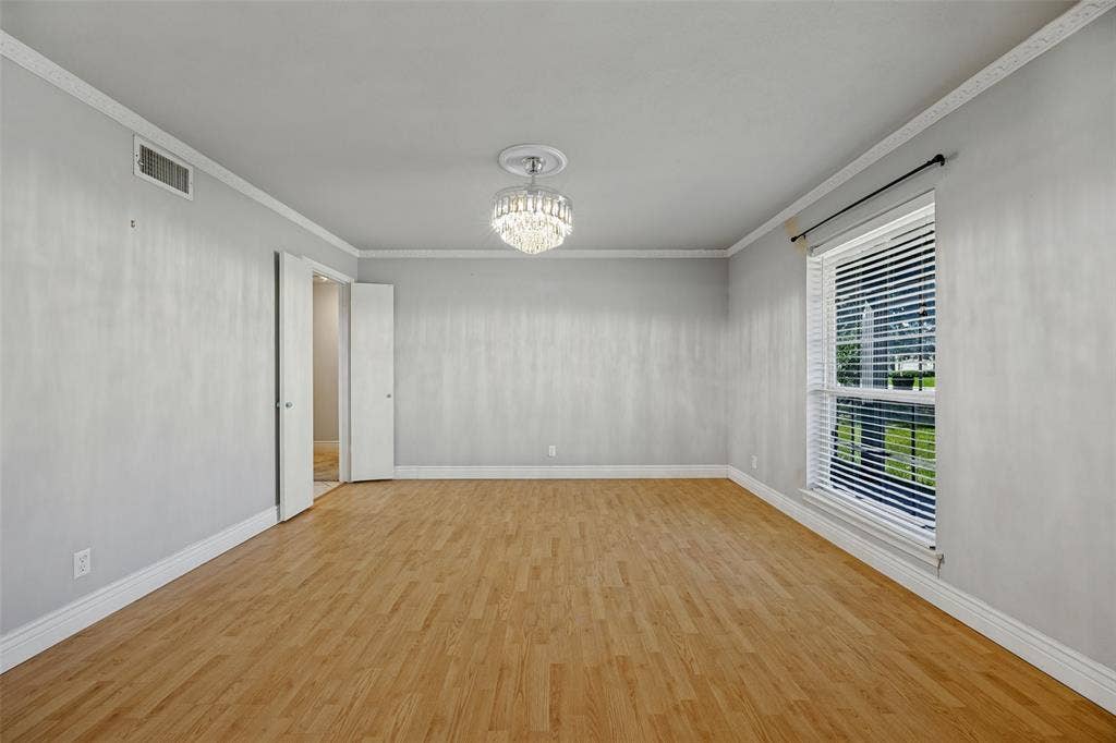 6401 Stonewall Street, Greenville, TX 75402 Wood-finish flooring, crown molding, double-door entry, decorative ceiling fixture, and a large window with blinds