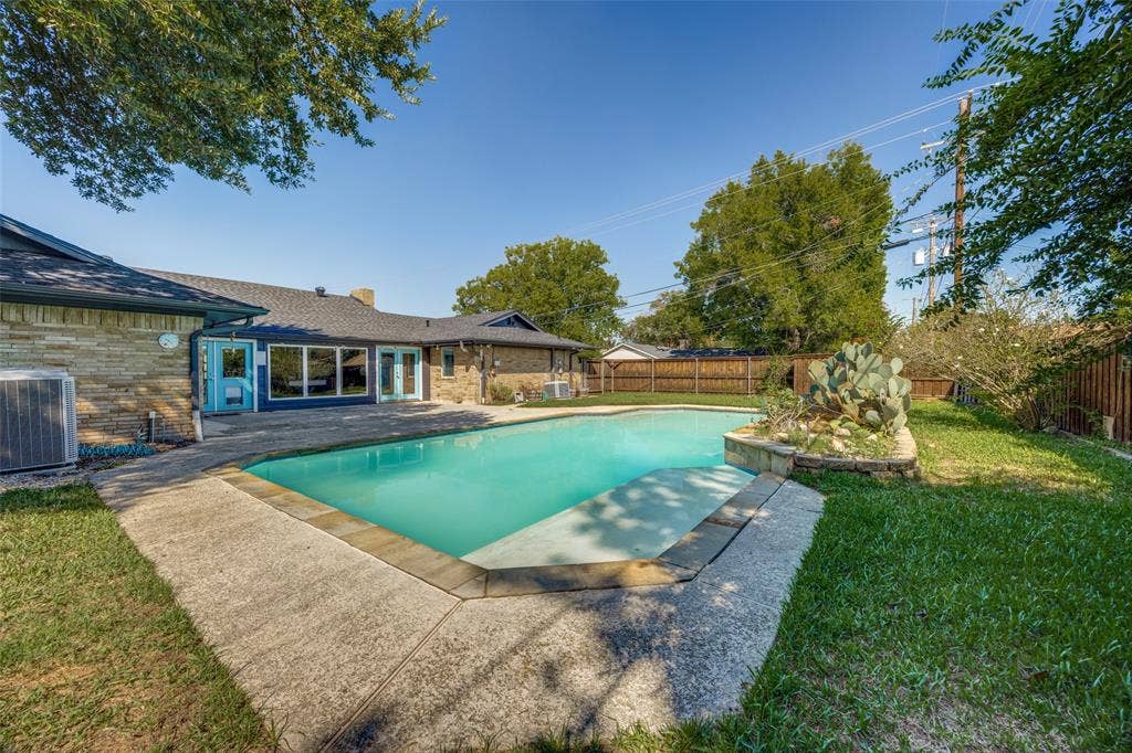 6401 Stonewall Street, Greenville, TX 75402 In-ground swimming pool with a concrete surround, stone planter, and fenced perimeter