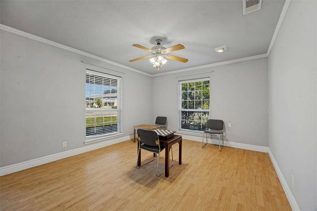 6401 Stonewall Street, Greenville, TX 75402 Wood-finish flooring with white baseboards, two windows with blinds, and a ceiling fan with integrated lighting