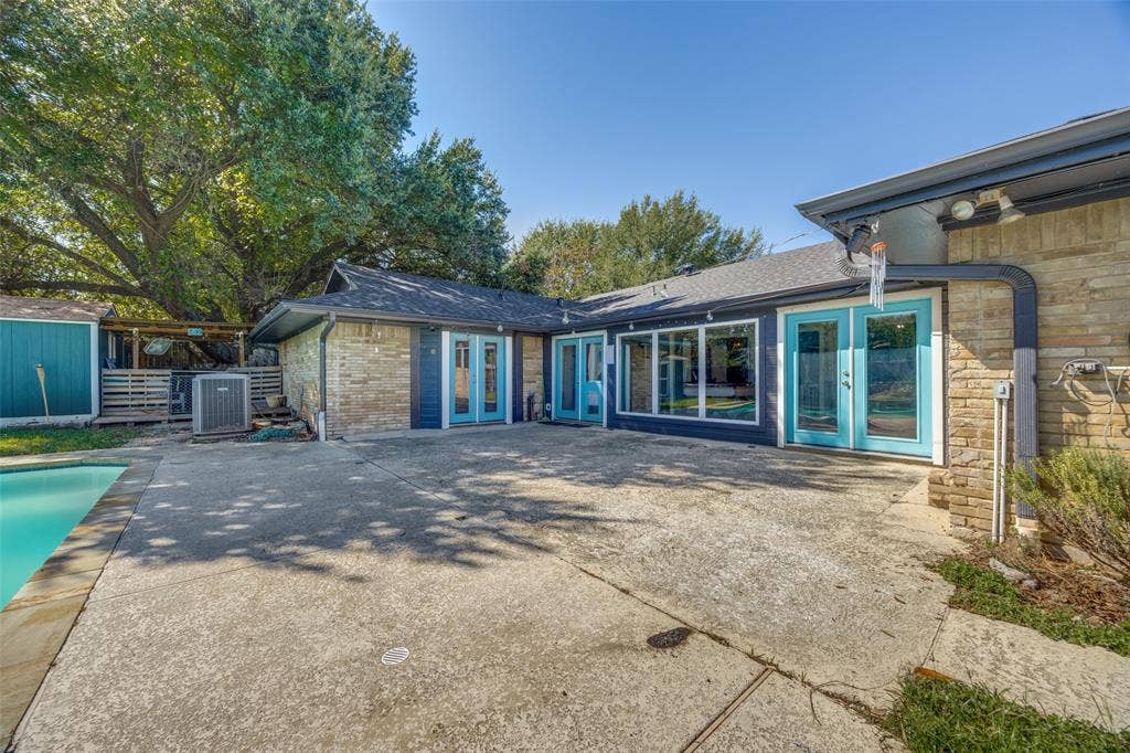 6401 Stonewall Street, Greenville, TX 75402 Expansive concrete patio with a swimming pool, stone exterior, and multiple glass-paneled doors