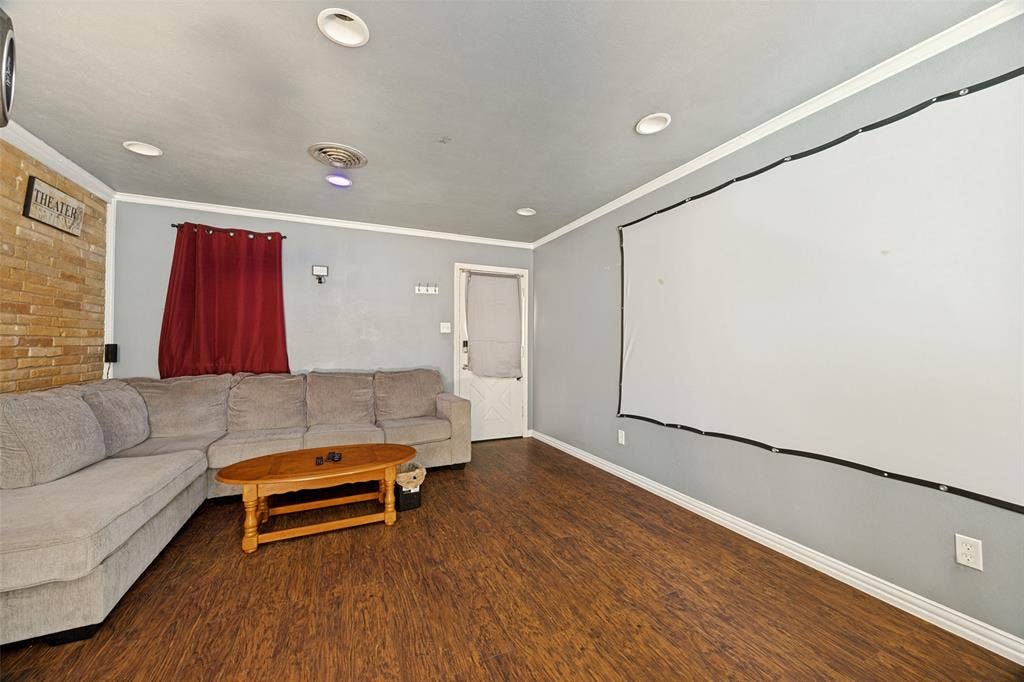 6401 Stonewall Street, Greenville, TX 75402 Wood-finish flooring with recessed lighting, crown molding, and a light-colored brick accent wall