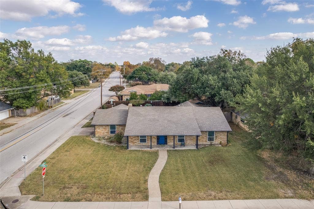 6401 Stonewall Street, Greenville, TX 75402 Single-story stone exterior home with a covered front porch, a blue front door, and a paved walkway