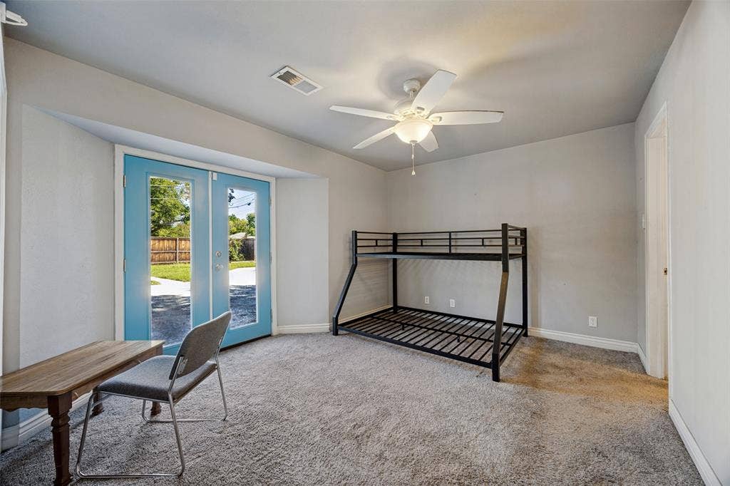 6401 Stonewall Street, Greenville, TX 75402 Carpeted room featuring a ceiling fan, light gray walls, and blue-framed glass panel double doors providing direct exterior access