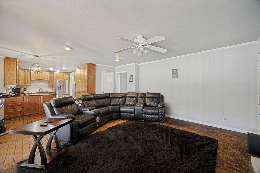6401 Stonewall Street, Greenville, TX 75402 Open-concept living space featuring wood-finish flooring, a ceiling fan with integrated lighting, recessed lighting, and a kitchen with wood cabinetry and stainless steel appliances