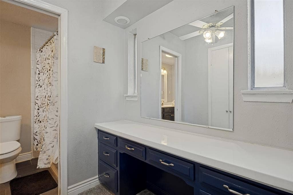 6401 Stonewall Street, Greenville, TX 75402 Extended vanity with multiple drawers, white countertop, and expansive wall mirror
