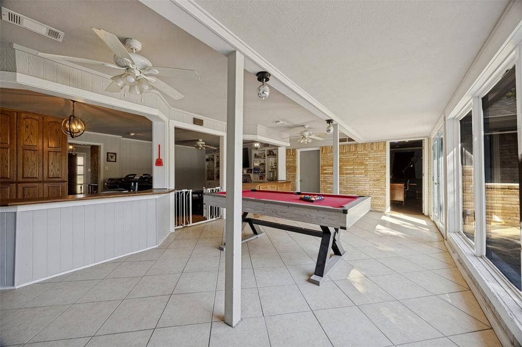 6401 Stonewall Street, Greenville, TX 75402 Expansive room with tiled flooring, a built-in bar with wood cabinetry, and a wall of large windows
