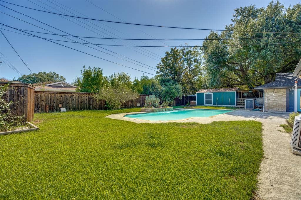 6401 Stonewall Street, Greenville, TX 75402 Expansive backyard featuring a swimming pool, concrete patio, a detached storage shed, and mature perimeter trees