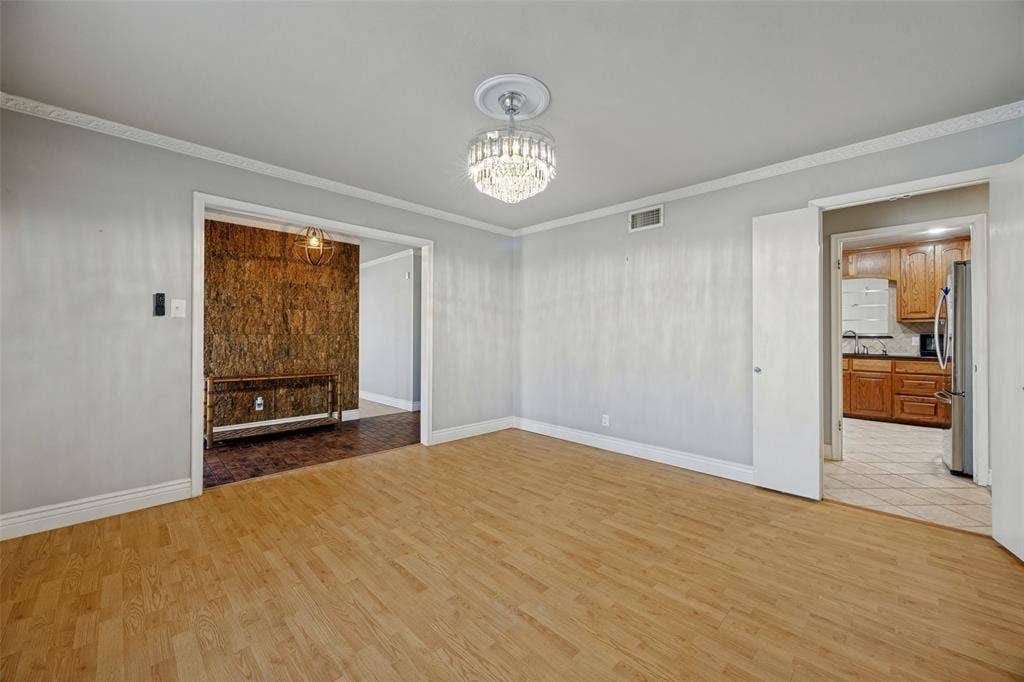 6401 Stonewall Street, Greenville, TX 75402 Light wood-finish flooring, crown molding, and a crystal chandelier