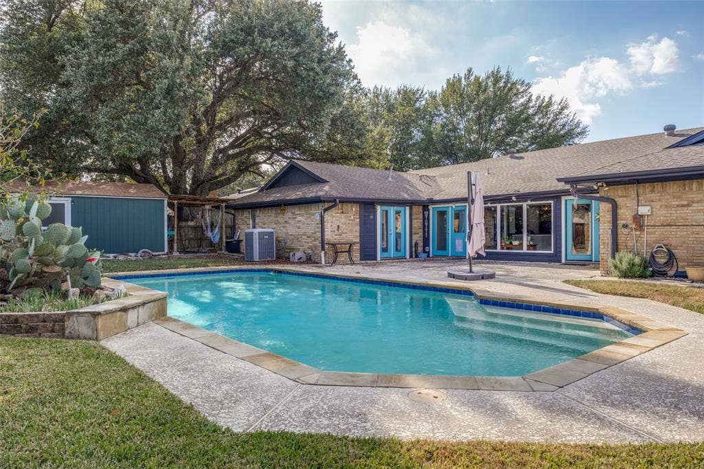 6401 Stonewall Street, Greenville, TX 75402 Backyard featuring a built-in swimming pool with integrated steps, a surrounding concrete patio, and a separate storage shed