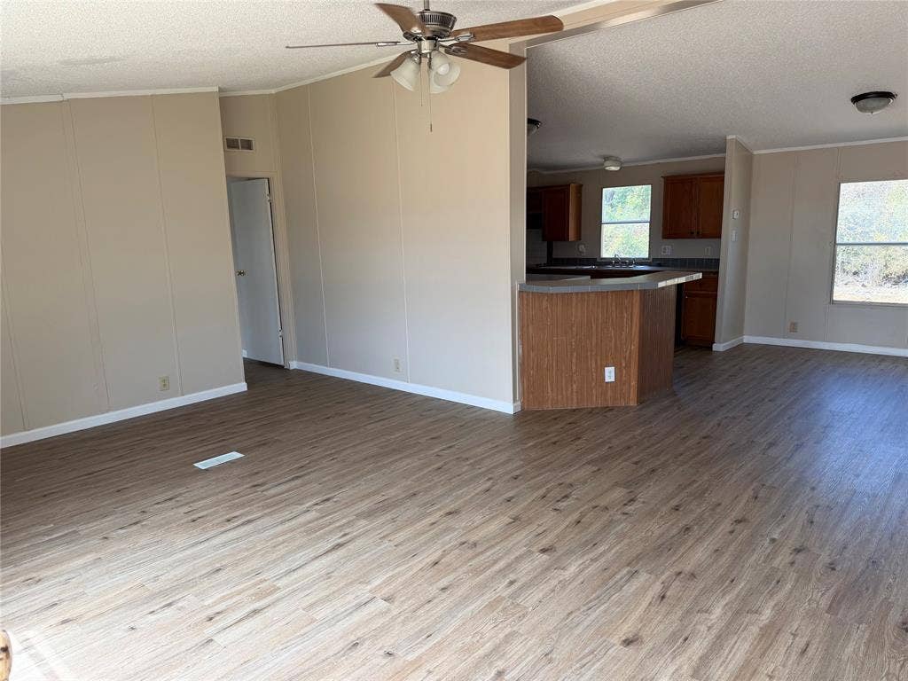 143 Summit Ridge Lane, Springtown, TX 76082 Open-concept living area with wood-finish flooring throughout, ceiling fan with brushed metal finish, and abundant natural light from multiple windows