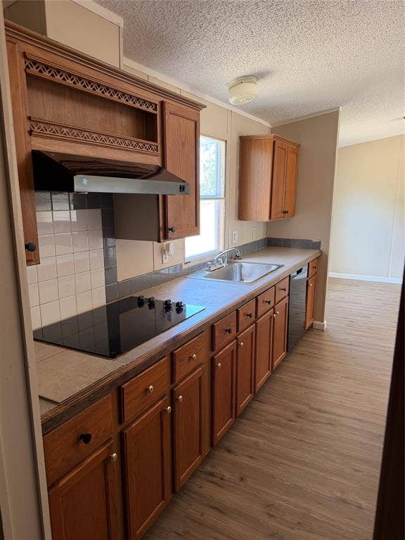 143 Summit Ridge Lane, Springtown, TX 76082 Well-appointed kitchen featuring wood-finish cabinetry, tile backsplash, built-in cooktop, stainless steel dishwasher, and wood-finish flooring