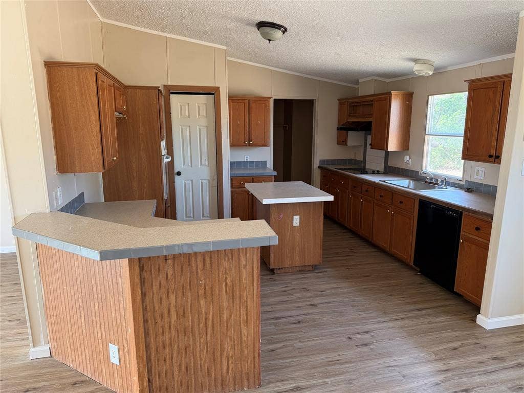 143 Summit Ridge Lane, Springtown, TX 76082 Kitchen featuring wood-finish cabinetry, a central island, a breakfast bar, wood-finish flooring, and a stainless steel sink