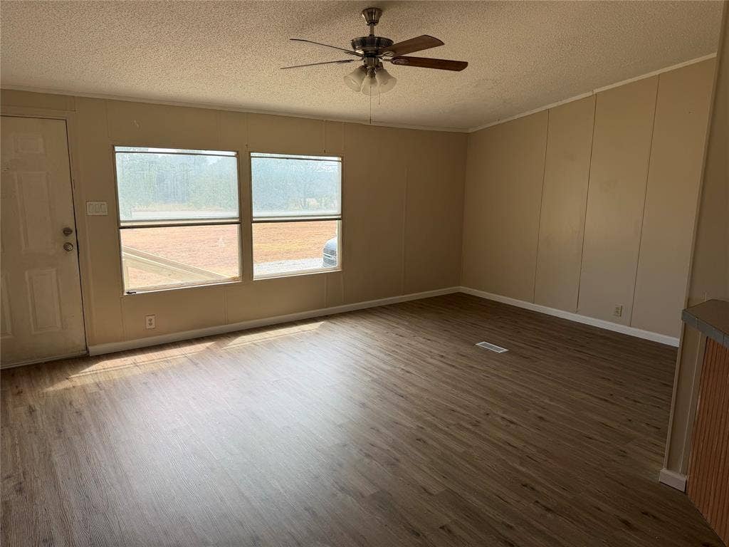 143 Summit Ridge Lane, Springtown, TX 76082 Spacious room featuring wood-finish flooring, ceiling fan with integrated lighting, large dual-pane windows with natural light exposure, and neutral wall finishes throughout
