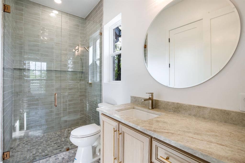 Glass-enclosed shower with horizontal tile surround and mosaic floor