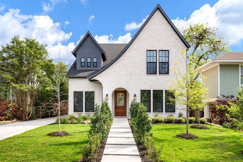 White brick exterior with dark trim accents, gabled roofline, and dormer window