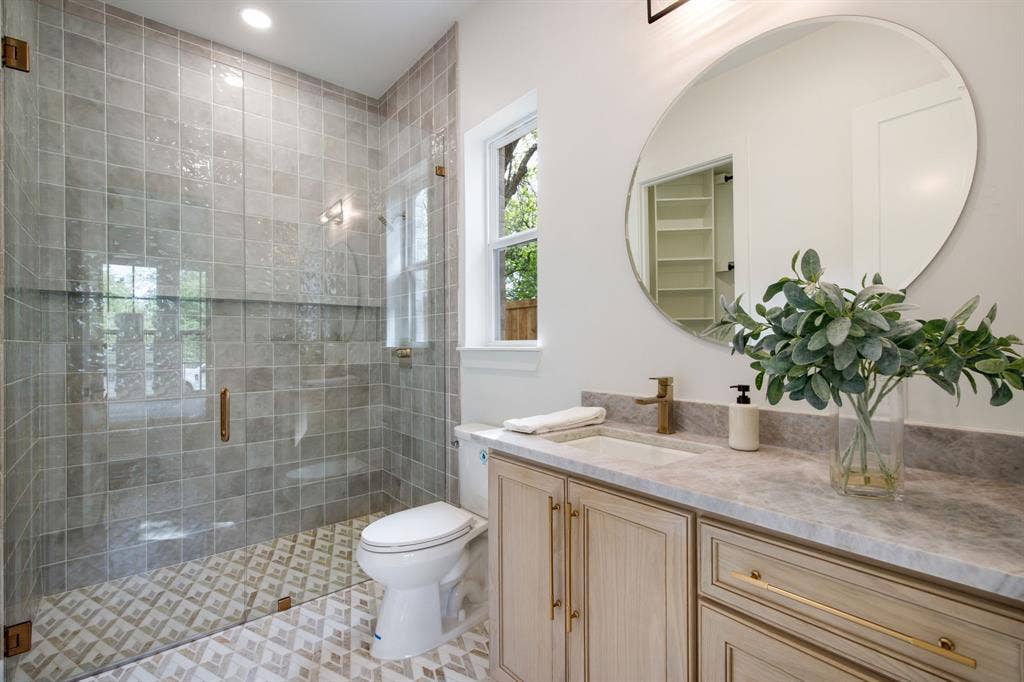 Glass-enclosed shower with tiled walls and patterned floor