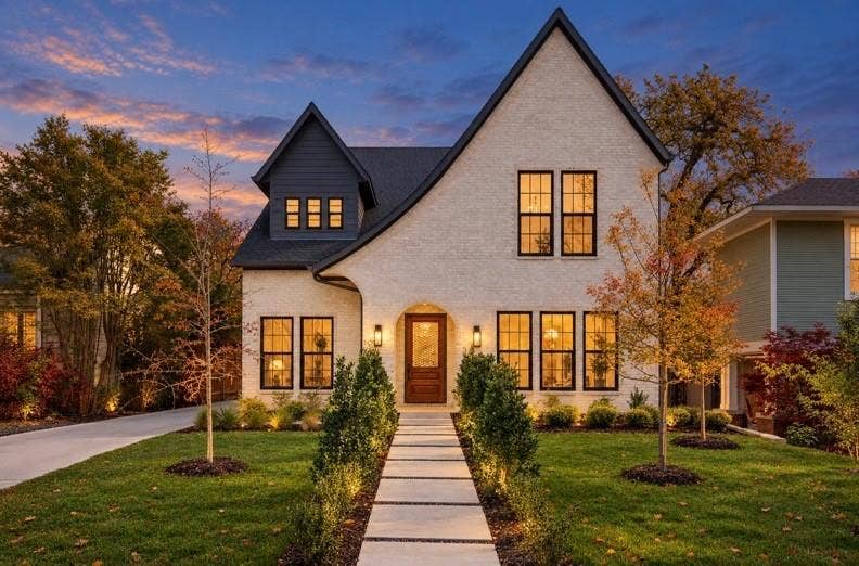 White brick exterior with a dark shingle roof and a prominent gable